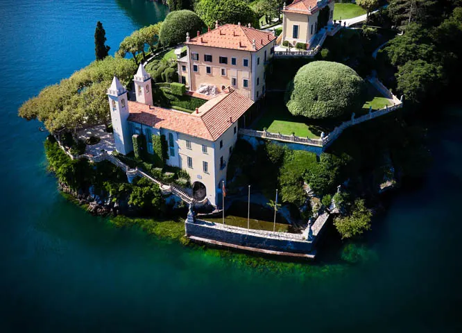Una villa su un promontorio del lago, fra giardini e acqua verde smeraldo, vista dall’alto