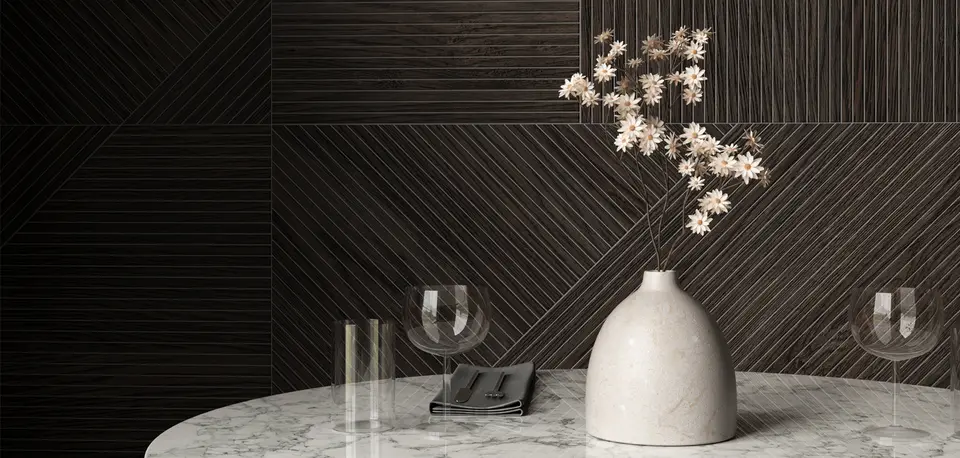 Una parete a boiserie scura a righe oblique, un tavolo di marmo con un vaso di fiori chiari