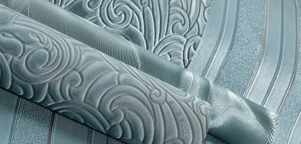 Un rotolo di carta da parati Elie Saab color acqua, goffrato a volute e righe in rilievo